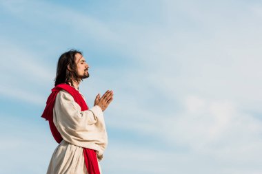 man with closed eyes praying against blue sly  clipart