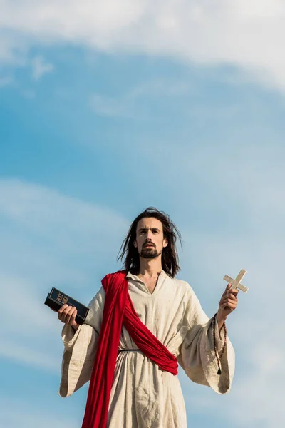 Jesus Sosteniendo Biblia Santa Cruz Contra Cielo Azul Con Nubes — Foto de Stock