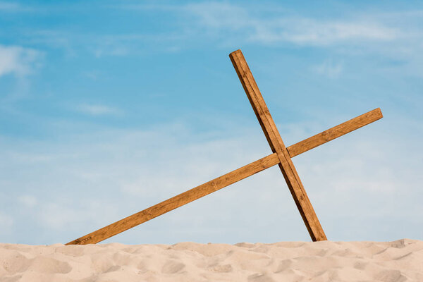 wooden cross on wavy and golden sand in desert 