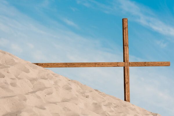 wooden cross on golden and wavy sand in desert 