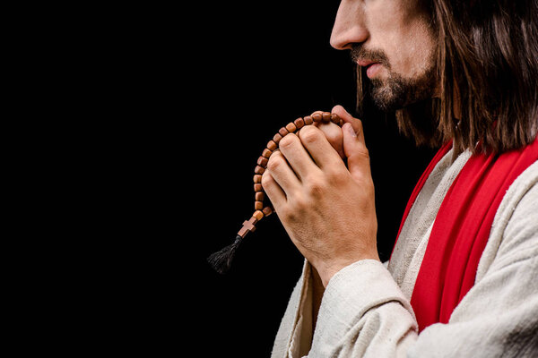 side view of man holding rosary beads isolated on black 