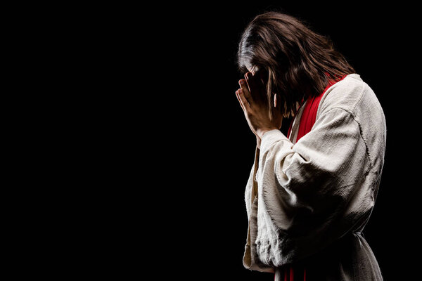 religious man covering face while praying isolated on black 