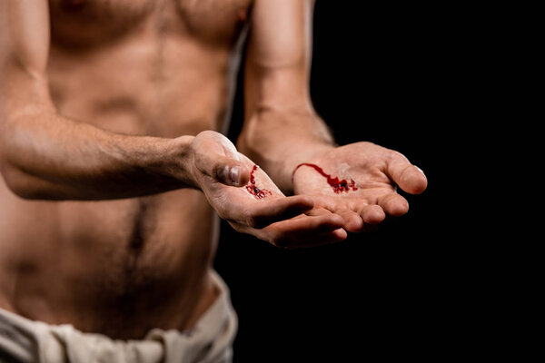 selective focus of jesus with bloody hands isolated on black 