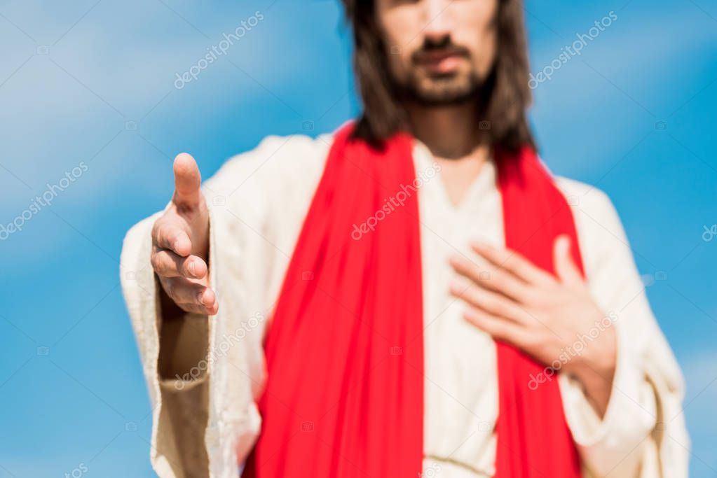 cropped view of jesus gesturing against blue sky 