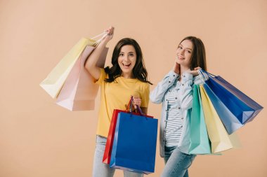 bej izole alışveriş çantaları tutan çekici ve gülümseyen arkadaşlar