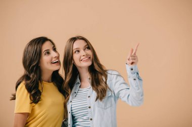 çekici ve gülümseyen arkadaşlar bej izole parmak ile işaret 