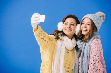 mavi izole selfie alarak kazak ve eşarp çekici ve gülümseyen kadınlar
