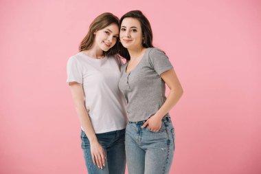 pembe izole kamera bakarak t-shirt çekici ve gülümseyen kadınlar