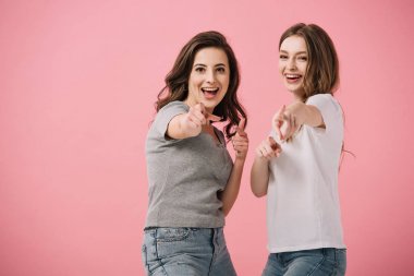 pembe izole parmakları ile işaret t-shirt çekici ve gülümseyen kadınlar