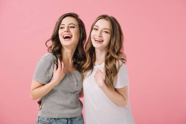 attractive and smiling women in t-shirts looking at camera isolated on pink clipart