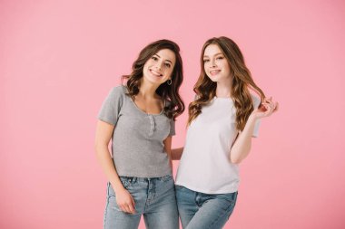 pembe izole kamera bakarak t-shirt çekici ve gülümseyen kadınlar
