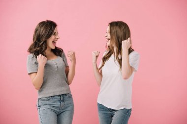 attractive and smiling women in t-shirts showing yes gestures isolated on pink clipart