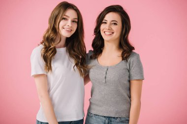 pembe izole kamera bakarak t-shirt çekici ve gülümseyen kadınlar