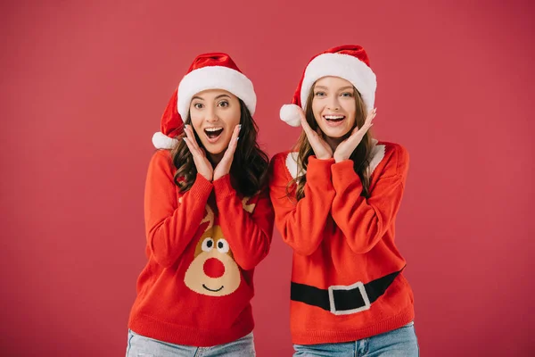 Mujeres Atractivas Sonrientes Suéteres Sombreros Santa Mirando Cámara Aislada Rojo — Foto de Stock