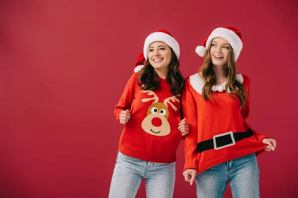 Attractive Smiling Women Sweaters Santa Hats Looking Away Isolated Red — Stock Photo, Image