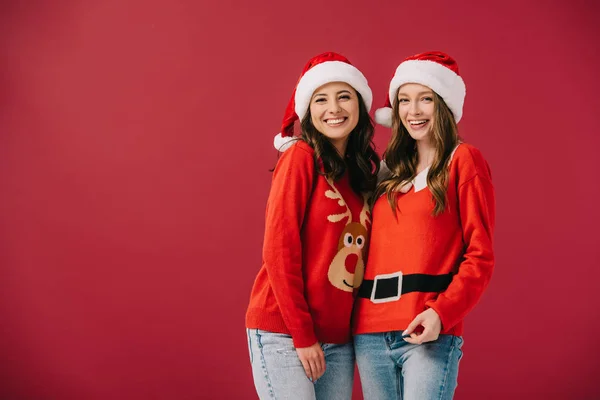 Mujeres Atractivas Sonrientes Suéteres Sombreros Santa Mirando Cámara Aislada Rojo — Foto de Stock