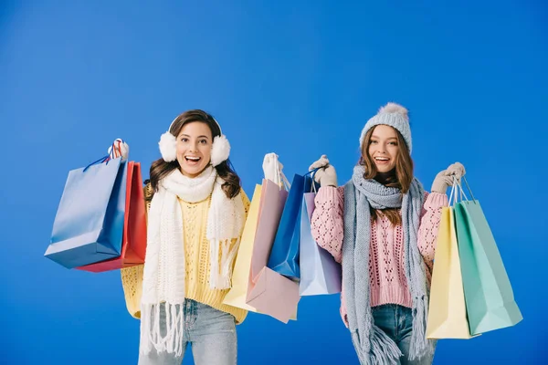 Mulheres Atraentes Sorridentes Suéteres Cachecóis Segurando Sacos Compras Isolados Azul — Fotografia de Stock