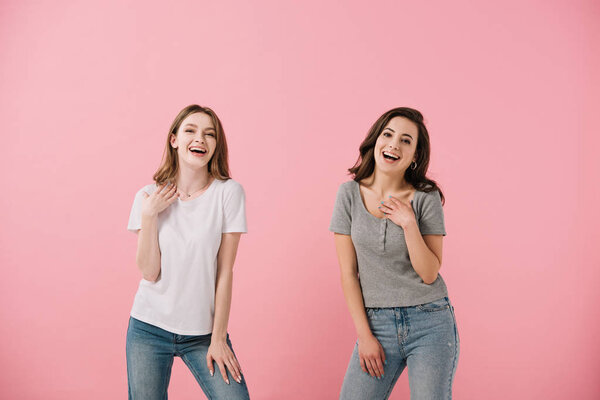 привлекательные и улыбающиеся женщины в футболках, смотрящие на камеру, изолированную на розовом
