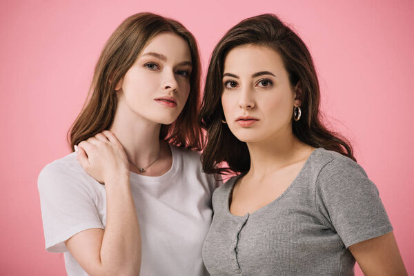 attractive women in t-shirts looking at camera isolated on pink