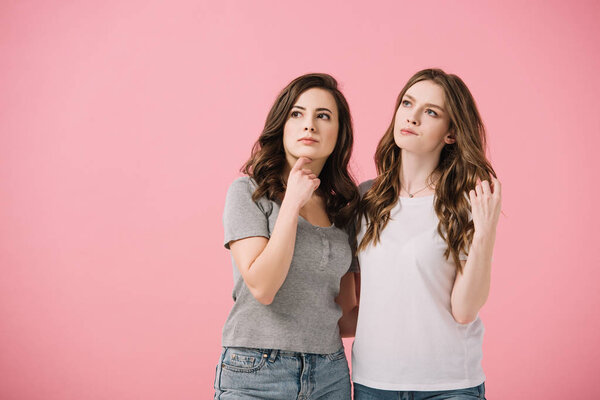 attractive and pensive women in t-shirts looking away isolated on pink