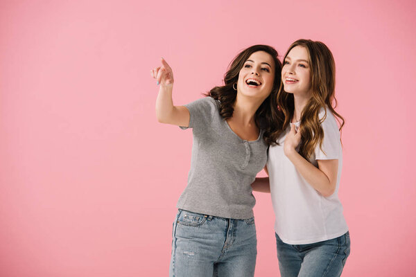 привлекательные и улыбающиеся женщины в футболках, указывающие пальцем на розовый
