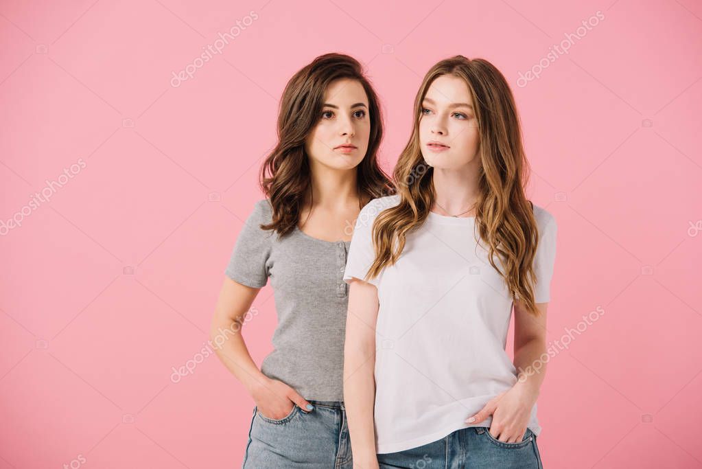 Attractive women in t-shirts looking away isolated on pink