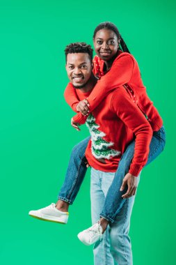 Afrikalı Amerikalı adam yeşil izole Noel kazak arka kadın tutarak