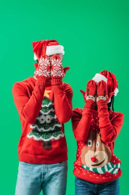 Kırmızı Noel kazak ve Santa şapkalı Afro-Amerikan çift yeşil izole desen ile kış eldiven elleri ile gözleri kapsayan