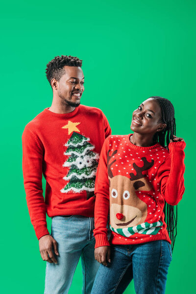 African American man and woman in Christmas sweaters isolated on green