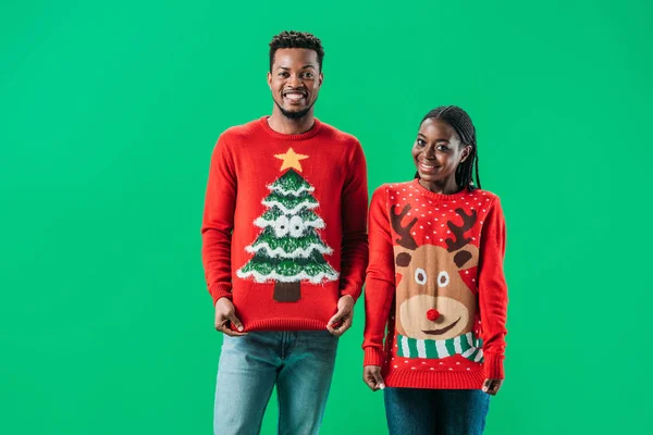 非洲裔美国男子接近女人在红色圣诞毛衣微笑 看着相机孤立在绿色 — 图库照片