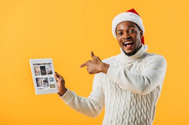 Kiev, Ukrayna - 2 Ağustos 2019: Noel Baba şapkalı Afro-Amerikan adam ebay web sitesi sarı izole ile dijital tablet parmak ile işaret