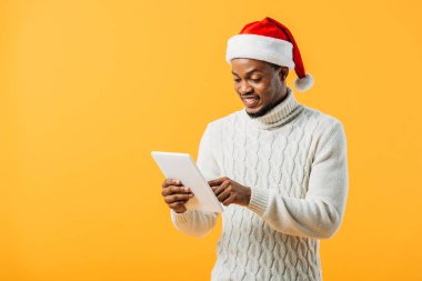 Sarı izole dijital tablet kullanarak Santa şapka Lı Amerikalı adam