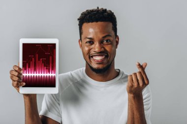 Afro-Amerikan adam iş grafikleri ile dijital tablet tutan ve gri izole para jest gösteren