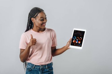 Afro-Amerikan kadın iş grafikleri ile dijital tablet tutan ve gri izole başparmak gösteren