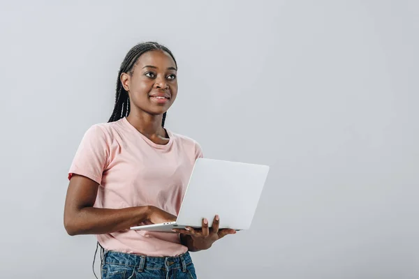 African American Kobieta Trzyma Laptopa Patrząc Dala Izolowane Szarym — Zdjęcie stockowe