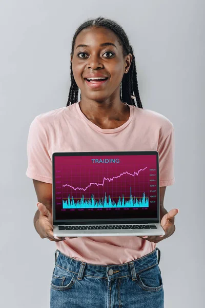 African American Woman Smiling Holding Laptop Trading Charts Isolated Grey — Stock Photo, Image