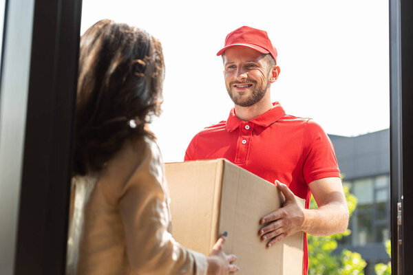 selective focus of happy delivery man giving box to woman 