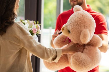 cropped view of woman receiving gifts from delivery man  