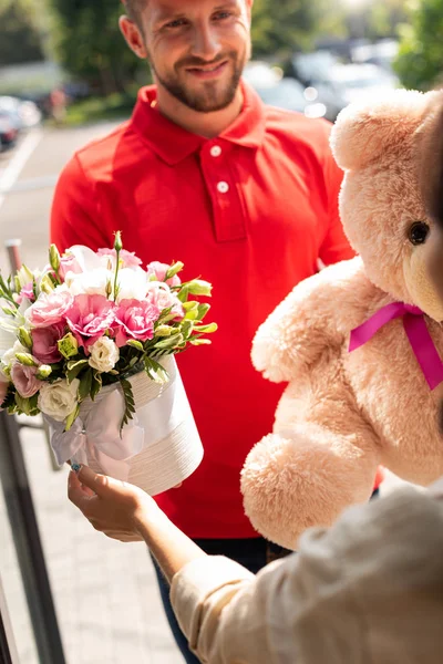 选择性的焦点快乐交付男子拿着泰迪熊和鲜花附近的女孩 — 图库照片