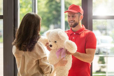 selective focus of happy bearded man giving teddy bear to woman  clipart