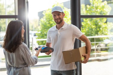 kredi kartı okuyucu ve teslimat adam yakınında akıllı telefon tutarken ödeme mutlu kadın 
