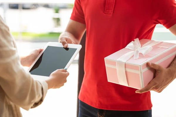 ピンクのプレゼントを持ち 女性にデジタルタブレットを与える配達人のトリミングされたビュー — ストック写真