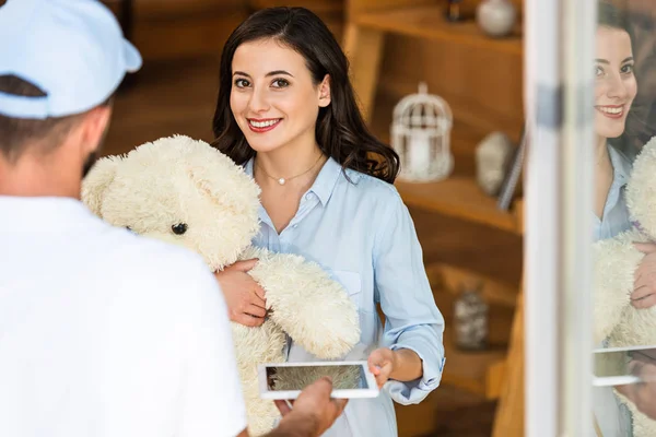 Back View Delivery Man Giving Digital Tablet Happy Woman Teddy — Stock Photo, Image