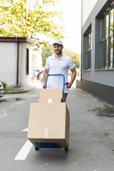 Positive Delivery Man Walking Delivery Cart Building — Stock Photo, Image