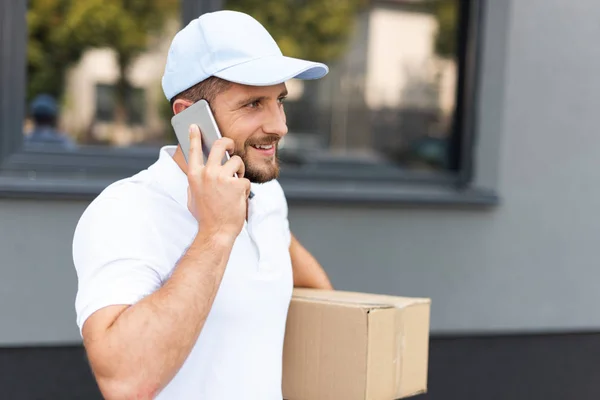 Homem Entrega Barbudo Feliz Falando Smartphone Enquanto Segurando Caixa — Fotografia de Stock