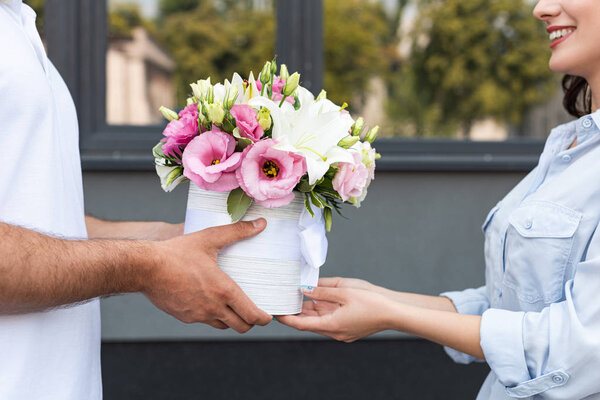 cropped view smiling girl receiving flowers from delivery man outside 