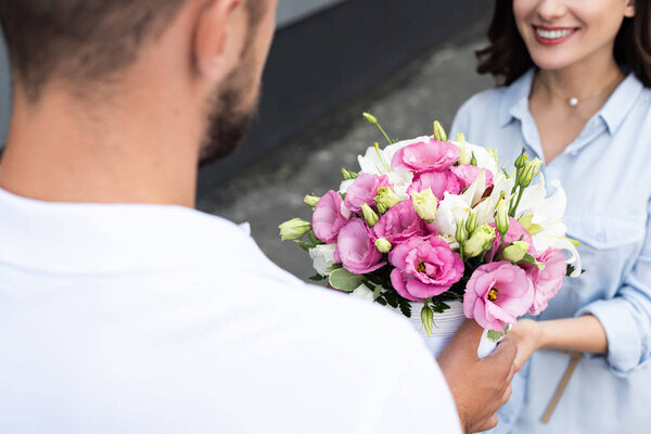 selective focus of happy girl receiving flowers from delivery man outside 