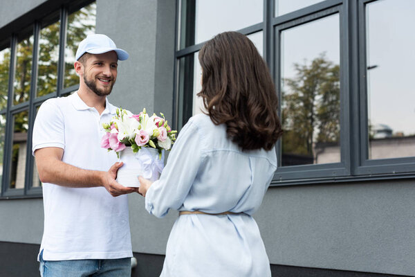 happy bearded man in cap giving flowers to woman outside 