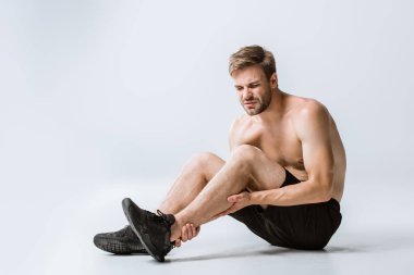 gri ayak bileği ağrısı ile gömleksiz sakallı sporcu