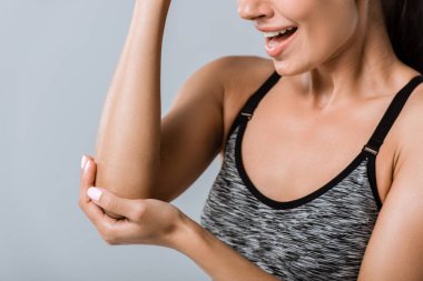 cropped view of sportswoman with elbow pain isolated on grey clipart